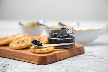 Schwarzer Kaviar auf Perlmuttlöffel mit Pfannkuchen, Eier Hack, Saure Sahne und Relish 