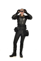full length portrait of female  soldier wearing black  tactical armour  holding  a pair of binoculars, isolated on white studio background.