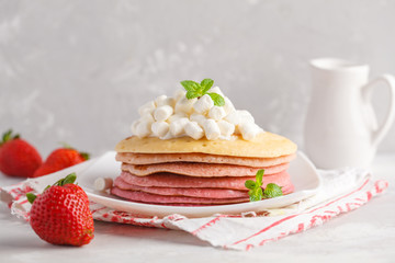 Stack of pink ombre  pancakes with marshmallow and strawberries. Breakfast background, copy space.