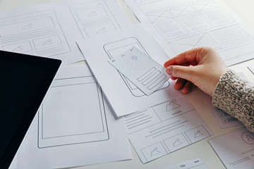 Web designer creating mobile responsive website. Website wireframe sketches on white table