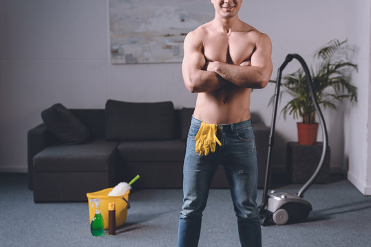 cropped image of sexy shirtless man standing with crossed arms, rubber gloves in jeans