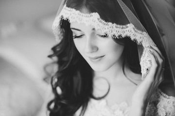 Portrait of the beautiful bride against a window indoors. black-white