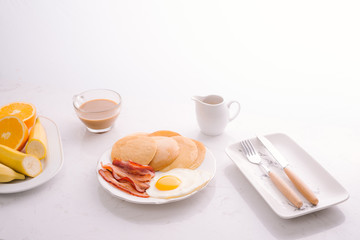 Breakfast plate with pancakes, eggs, bacon and fruit.