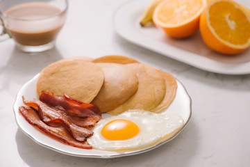 Breakfast plate with pancakes, eggs, bacon and fruit.
