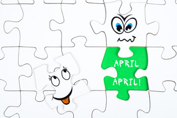 Puzzle pieces with tow funny faces and the words april, april