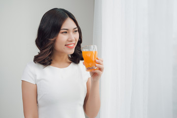 Beautiful asian girl drinking a glass of orange juice.