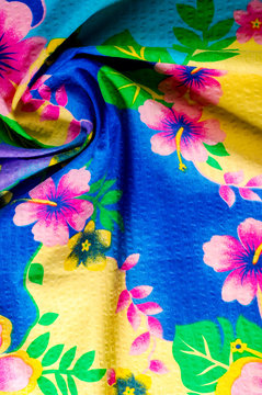 Texture, pattern. Cloth with patterned patterns of bright colors on a blue yellow background. Bright Batika fabric with a blue background and multi-colored flowers.