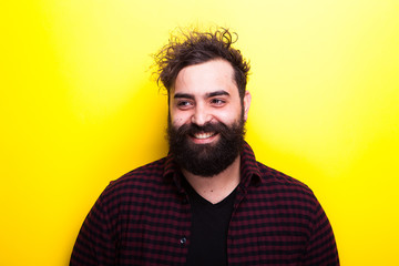 Caucasian bearded hipster smiling on yellow background