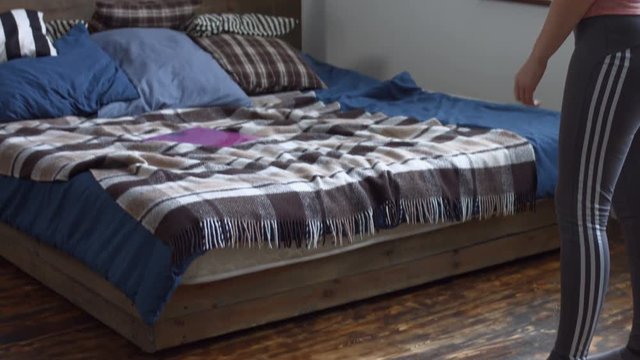 Frustrated redhead adult woman hurling weighing scales on bed after weight gain in domestic room. Furious charming female shocked by her own weight and throwing weight scales down on the bed.