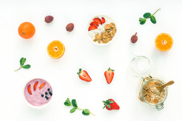 Healthy breakfast with yogurt, muesli, fruits, orange, berry, strawberry, blueberries on white background, flat lay, top view