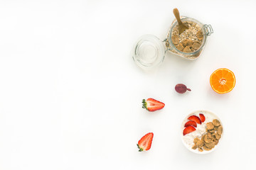 Healthy breakfast with yogurt, muesli, fruits, orange, berry, strawberry, blueberries on white background, flat lay, top view