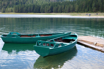 Boats on calm lake water. Green wooden boats.