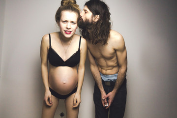 beautiful pregnant woman and her handsome boyfriend posing in lingerie
