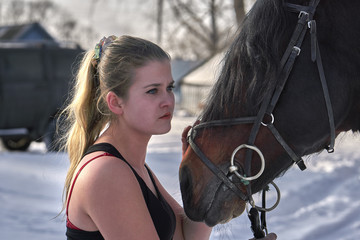 A girl with long blonde hair communicates with her favorite horse. The girl loves animals. Sunny...