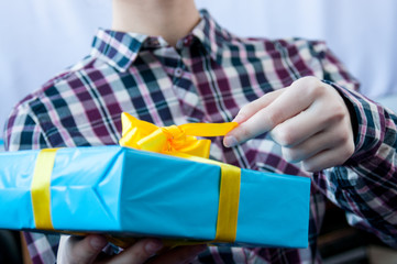 Hand untying a yellow bow on a gift
