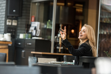 side view of smiling woman calling for waiter in restaurant