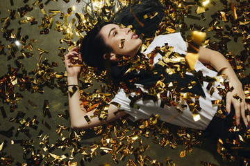 woman on the floor with golden confetti