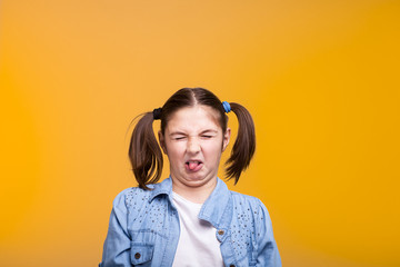 Girl in studio making a disgusted face with eyes closed on yellow background - obrazy, fototapety, plakaty