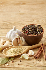 Composition of powder spices on spoon and different sorts of spicies on wooden table background, selective focus