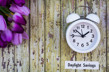 Daylight Savings Time Spring concept top down view with white clock and purple tulips