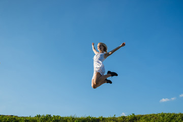 full lenth portrait of young woman is jumping on the meadow