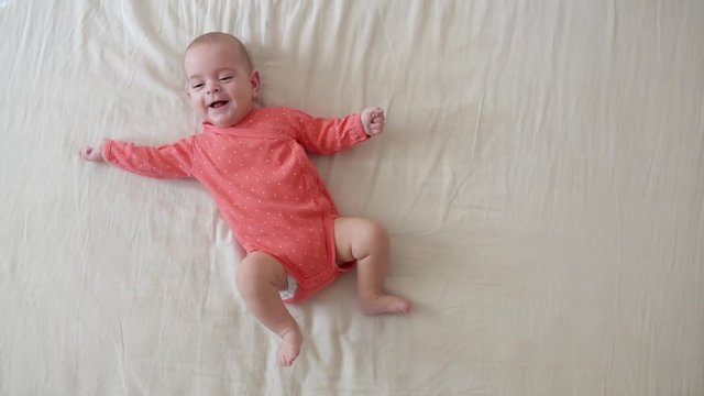 Adorable little happy newborn baby lying on the bed - top view