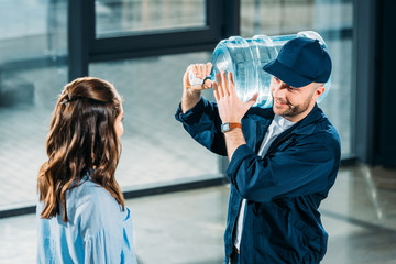 Woman looking at delivery man holding water bottle