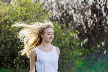Teenage girl in white dress is running in the spring garden