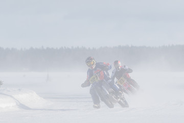 Motorcyclist racing on ice track in the middle of whirling snow