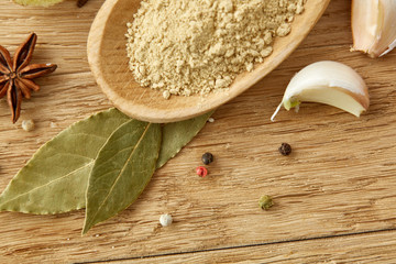 Composition of powder spices on spoon and different sorts of spicies on wooden table background, selective focus