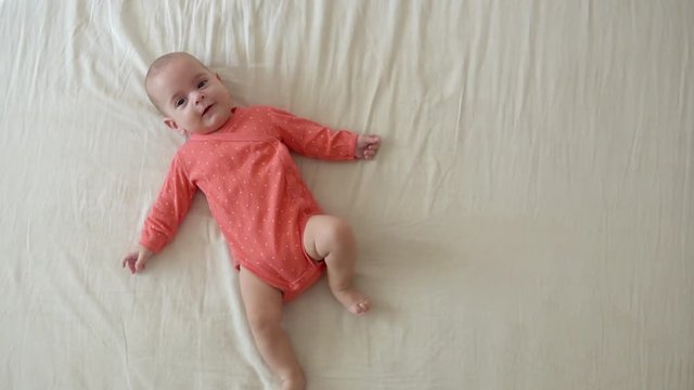 Cute little baby girl lying on the bed in pink body