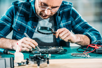 Repairman looking through magnifying glass while fixing circuit board