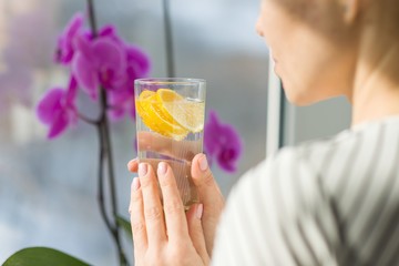 Woman drinking water with fresh organic lemon.
