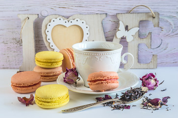 Traditional french macaroons, cup of tea, dry tea with rose buttons and letter 