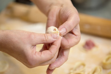  Hands  who prepares  homemade ravioli, pelmeni or dumplings from dough.Traditional Russian dish, national cuisine. Home cooking, handmade. Close-up.