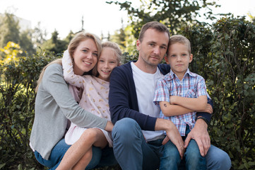 Mom and dad playing with their handsome son and daughter - Family and children outdoors in the park - Young beautiful family posing for the photographer