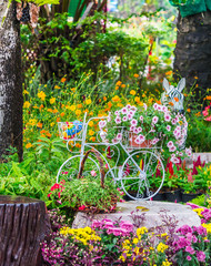 In een gezellige huistuin in de zomer. / Vintage witte fiets en bloempot in een gezellige huisbloementuin in de zomer.