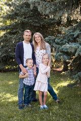 Obraz premium Mom and dad playing with their handsome son and daughter - Family and children outdoors in the park - Young beautiful family posing for the photographer