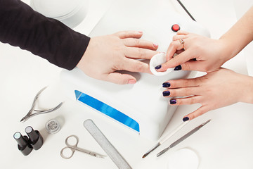 the girl does the manicure to the client. paints nails with gel-varnish. saws with a saw. beautiful, well-groomed hands