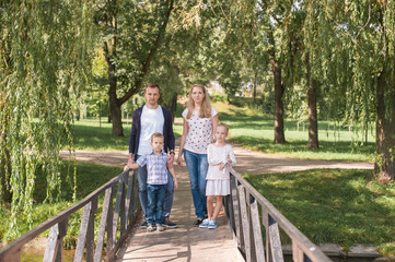 Mom and dad playing with their handsome son and daughter - Family and children outdoors in the park - Young beautiful family posing for the photographer