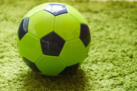 Football (Soccer) ball on a green surface imitating artificial grass. Sports photography 