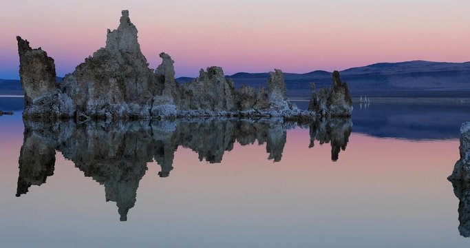 Mono lake tufas with reflection in calm water on sunset with zoom out effect