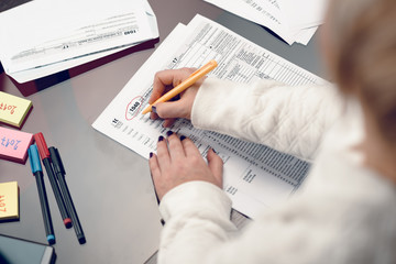Woman fills the tax form, working with tax documents.Form 1040 Individual Income Tax return form. United States Tax forms 2017/2018.