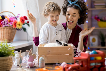 Portrait of happy young woman presenting pet bunny to cute little boy on Easter, copy space