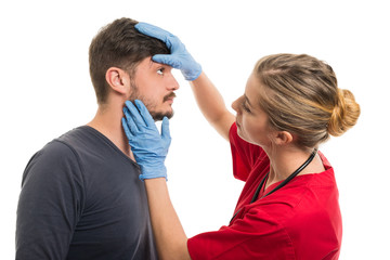 Female doctor checking male patient eye.