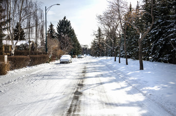 Naklejka premium Empty Snow Covered Street in a Residential District on Sunny Winter Day. 