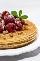 traditional thin pancakes with fresh raspberries on wooden table, vertical closeup