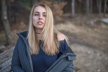 Obraz premium Beautiful natural young blonde woman wearing winter coat outside in the park winter time