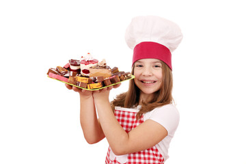 happy little girl cook with sweet cakes dessert on plate