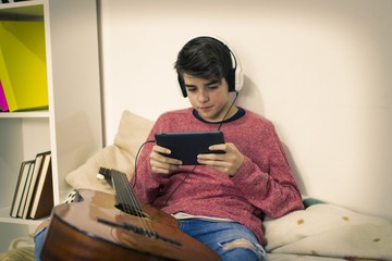 young man with computer and guitar in house room